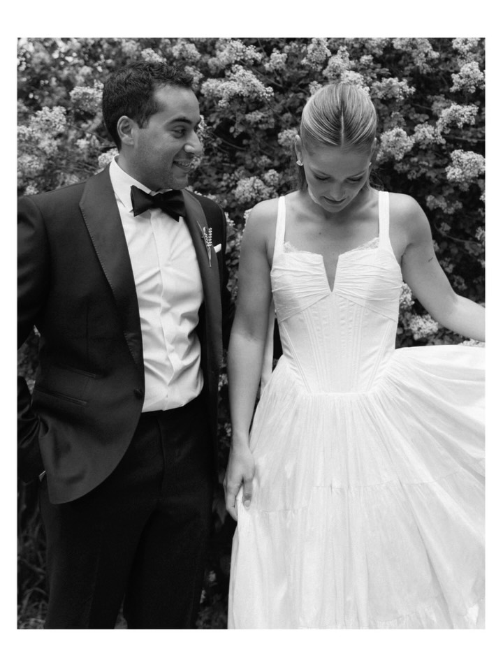 Couple in formalwear against a wall of white lilac, in black and white