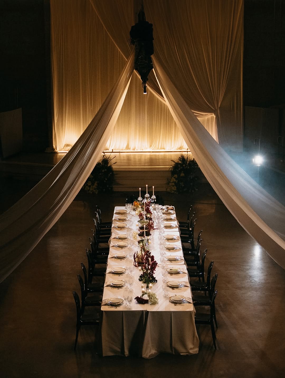 Sheer draping gathered like a cathedral over a candlelit dinner table set for a wedding