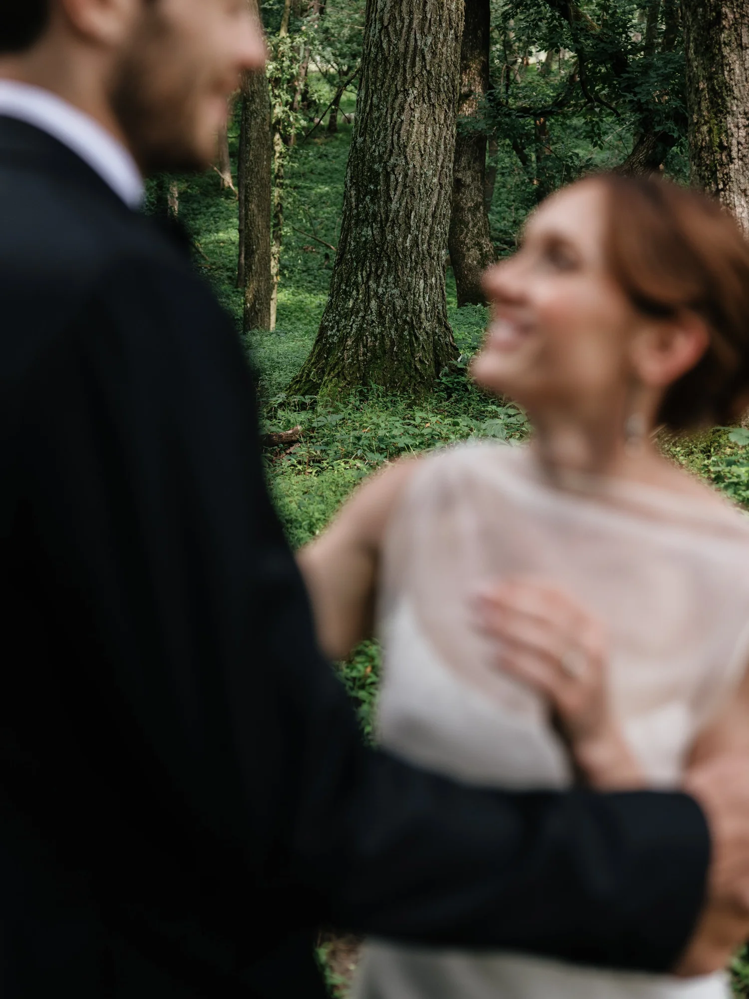 Hanna and Jared laughing among old-growth trees, soft-focus and green