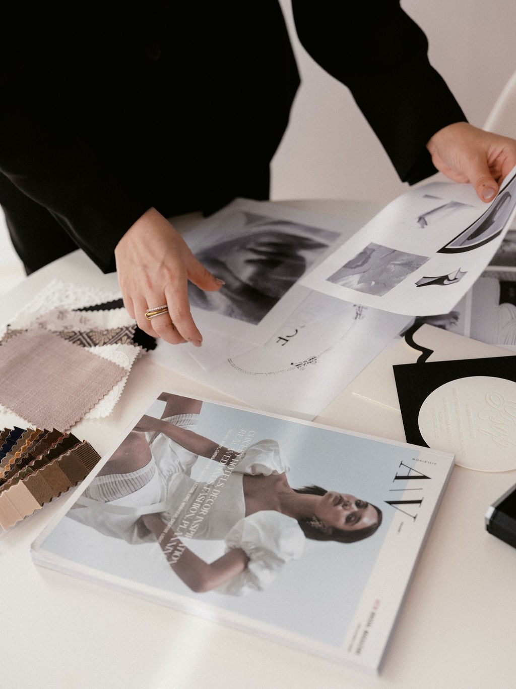 Steph's hands moving across moodboard pages, fabric swatches, and an embossed SERCE invitation suite